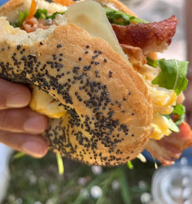 Bagel de semillas de amapola relleno de bacon, huevo y rúcula