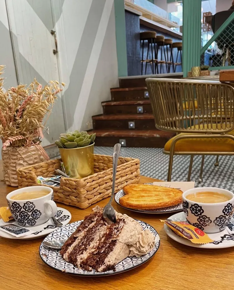 Porción de tarta de capas con dos cafés y una palmera