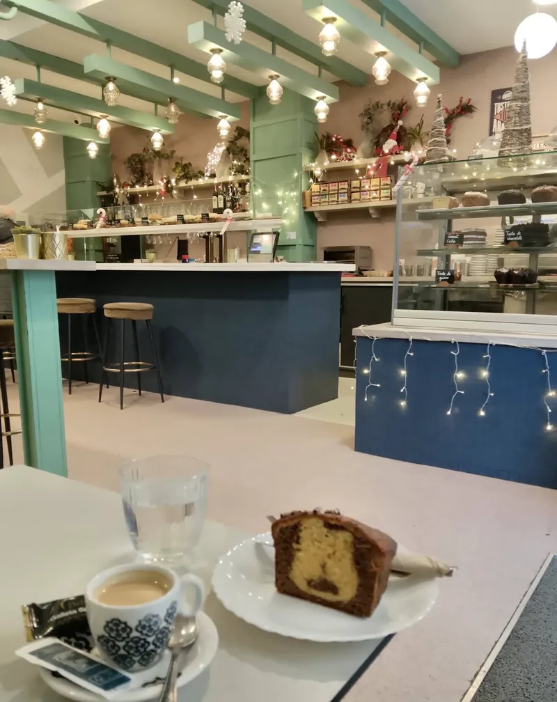 Interior de El Fontán con vigas verdes, barra azul marino y una porción de bizcocho