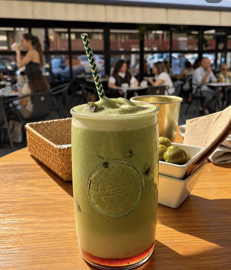 Bebida de matcha helada con pajita, en una mesa de terraza